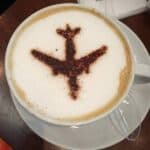 Latte with a silhouette of an airplane - More Coffee - Less Travel