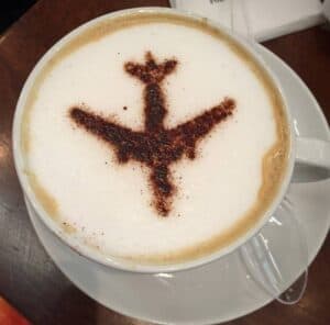 Latte with a silhouette of an airplane - More Coffee - Less Travel